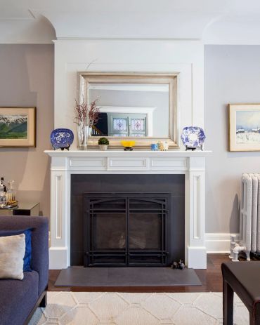 White fireplace mantel with mirror and decorative plates