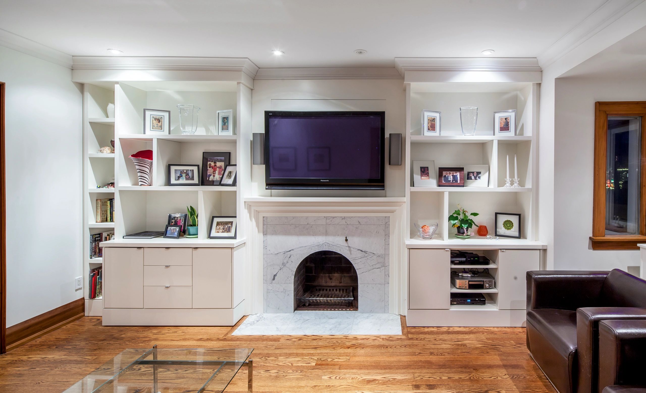 TV mounted above fireplace with built-in shelving